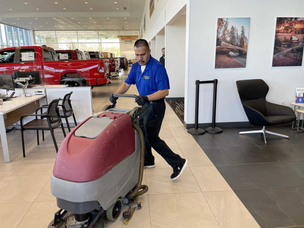 ROC Commercial Cleaning - man buffing a floor at an auto dealership 