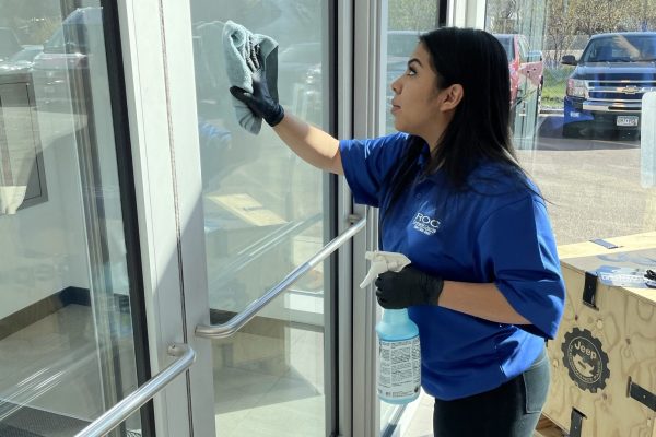 professional cleaner wiping down windows in entry way