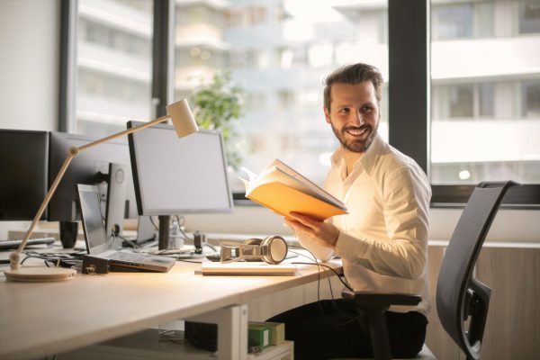 man at desk holding book