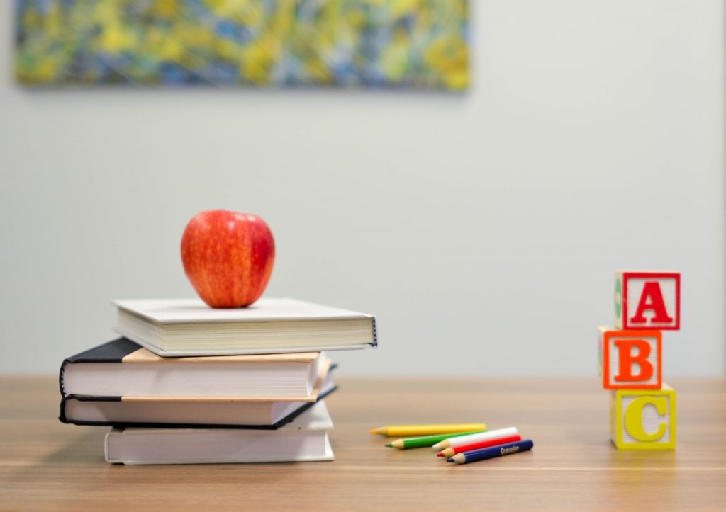 apple on pile of books on school desk