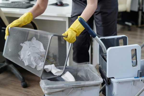 professional cleaner putting trash into janitor trolley