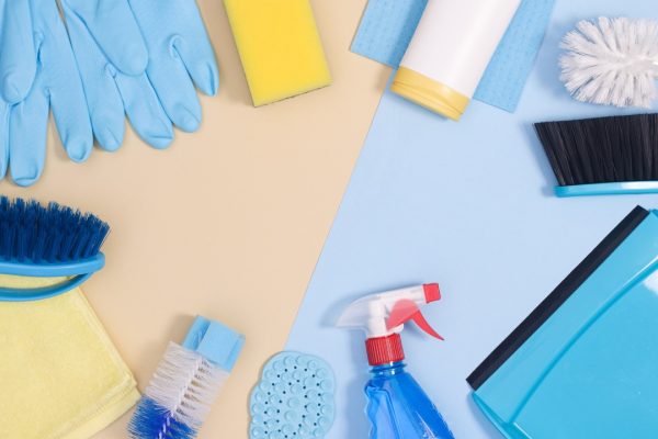 spring cleaning supplies on pastel blue and yellow background