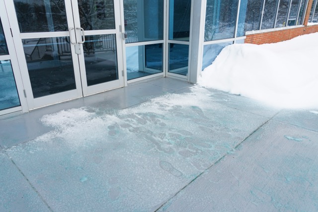 Melting salt and ice in front of entrance gate office building during winter