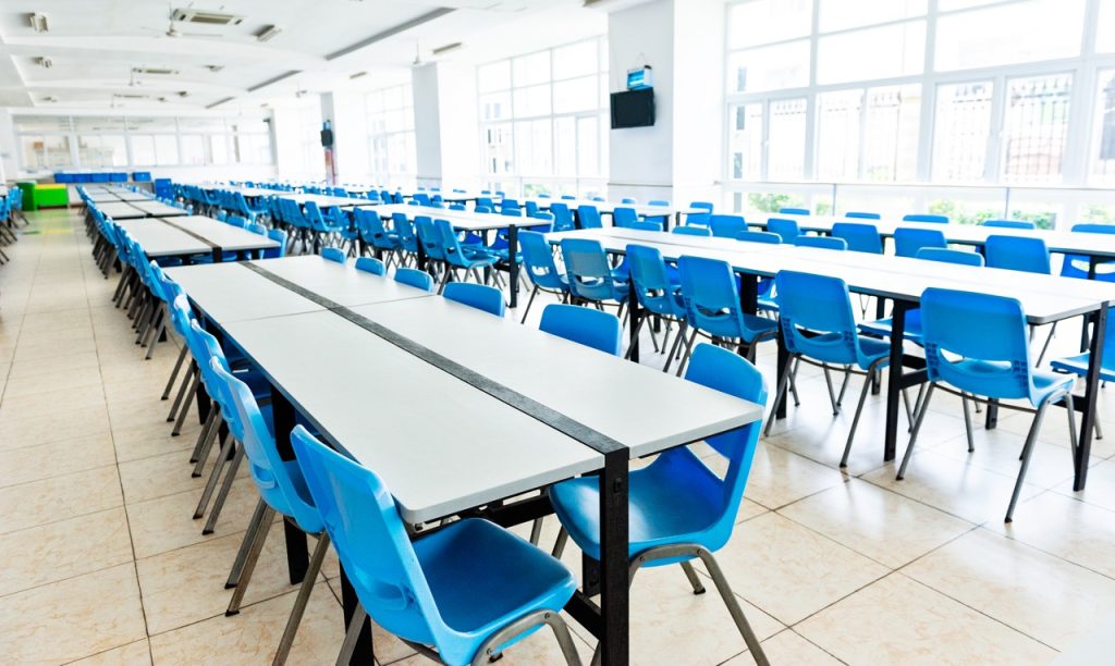 Bright school cafeteria with clean floors, tables, and chairs