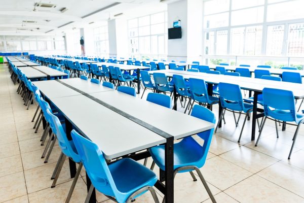Bright school cafeteria with clean floors, tables and chairs