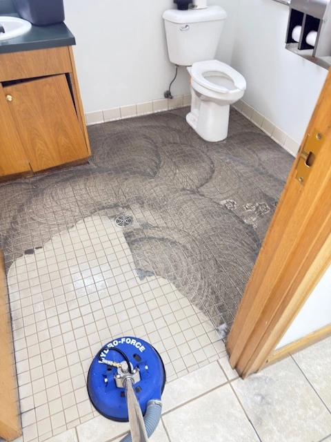 a bathroom floor being cleaned in an office space