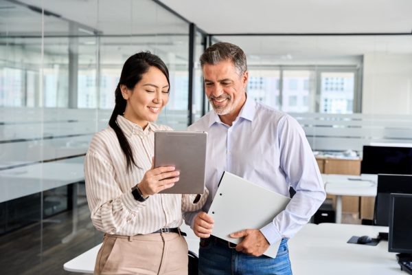 two business professionals standing in a office reviewing information on a tablet about commercial cleaning services